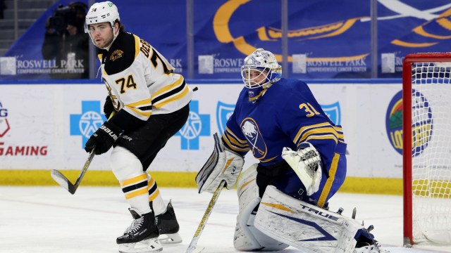 Boston Bruins left wing Jake DeBrusk (74) and Buffalo Sabres goaltender Dustin Tokarski (31)