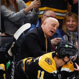 Boston Bruins head coach Jim Montgomery and forwards Johnny Beecher and Trent Frederic